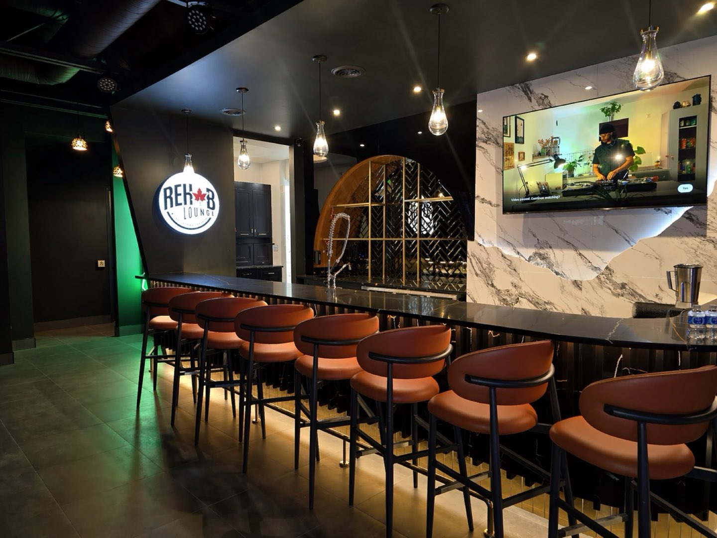 Inside Rehab Lounge — the black marble bar, leather stools and the gold arch