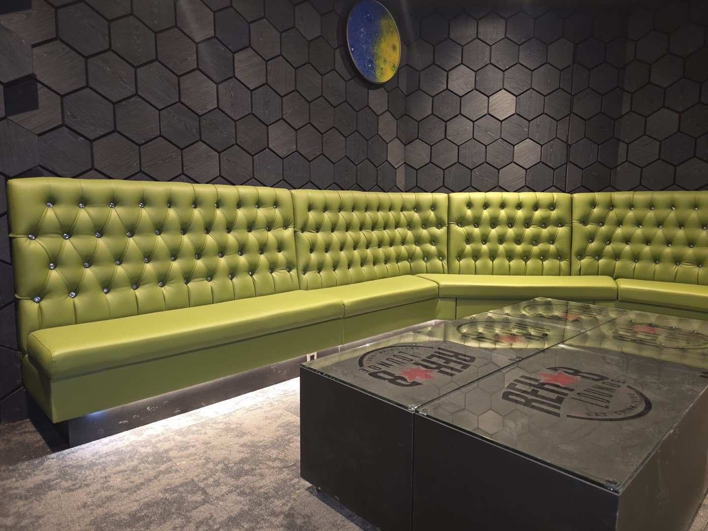 Green tufted booths around a table printed with the Rehab crest
